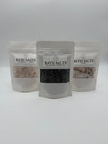 Three packages of bath salts with visible contents on a white background