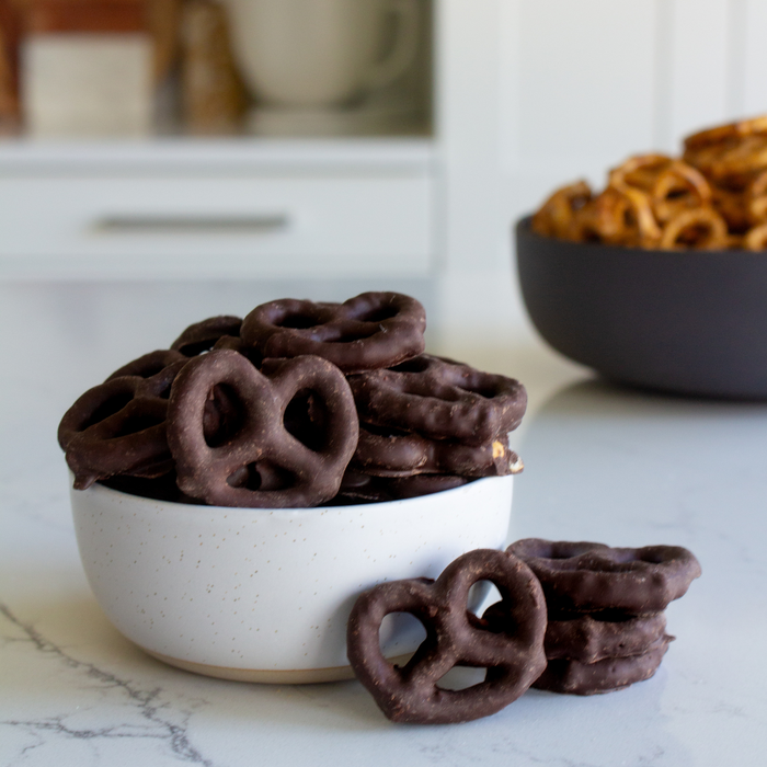 Bowl of JOJOs dark chocolate covered pretzels on a kitchen counter with a bowl of pretzels in the background