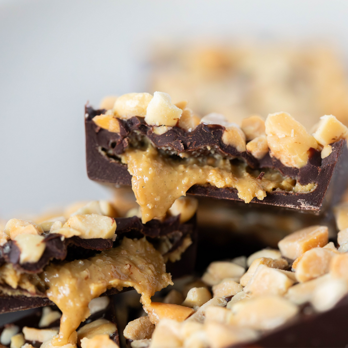 Close-up of a chocolate bar with creamy peanut butter filling and nuts on a light background