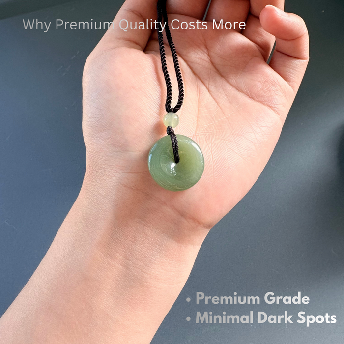 Hand holding natural green jade donut pendant