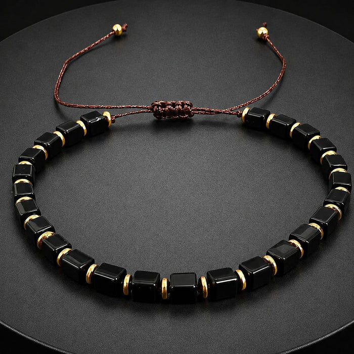 Adjustable black obsidian bracelet with gold accent beads close up